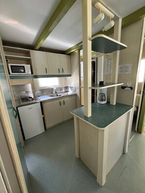 A compact kitchenette with a microwave, sink, and small refrigerator.