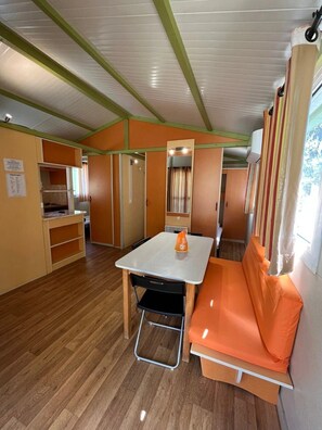 A compact RV interior with a kitchenette, a dining area, and a seating area.