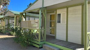 A row of small, single-story cabins with green railings and a covered porch.