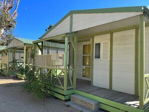 A row of small, single-story cabins with green railings and a covered porch.