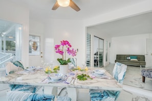 Un espace repas avec une table en marbre, des chaises et un ventilateur de plafond.