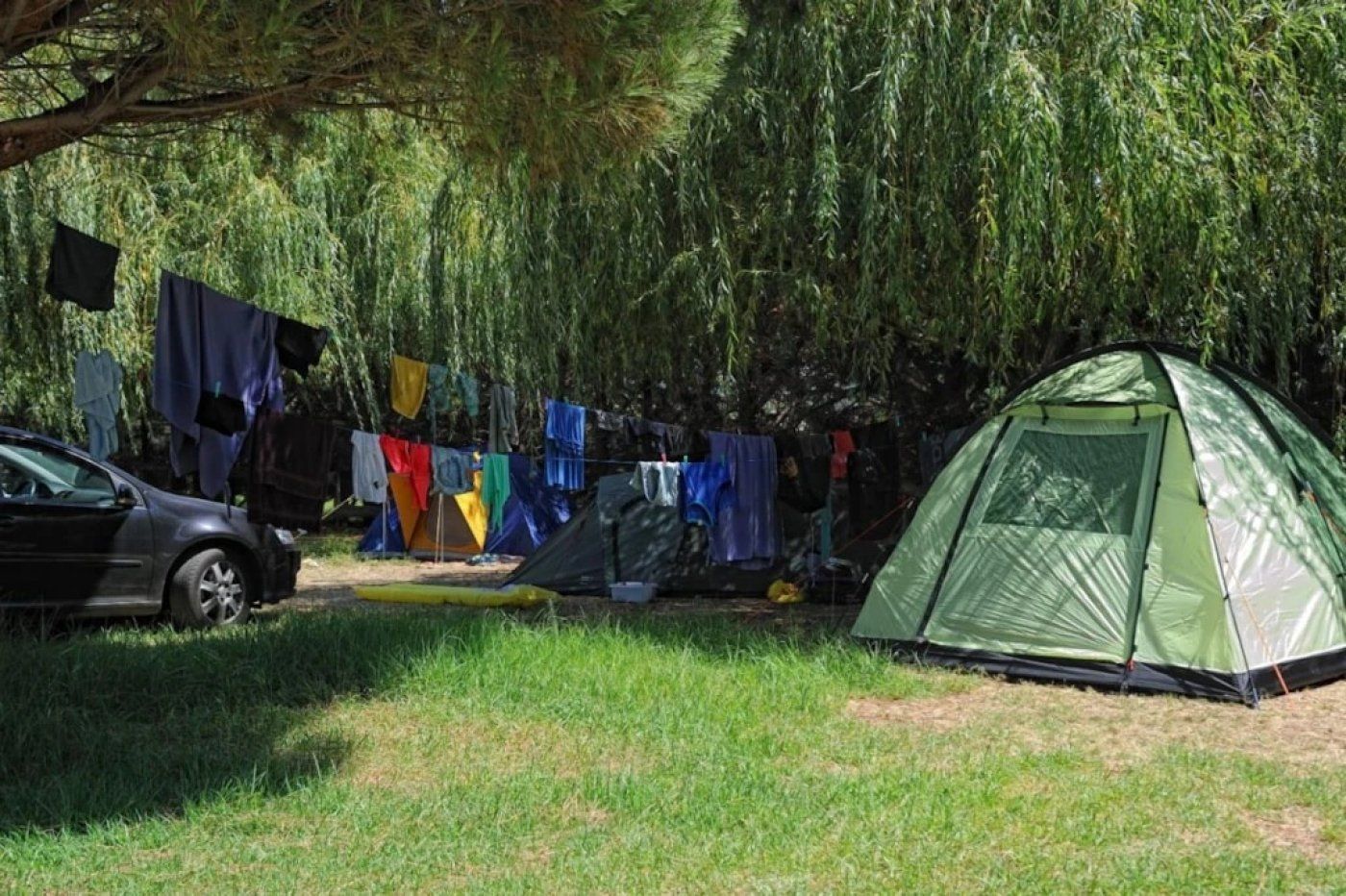 A camping area with a tent, a car, and clothes hanging on a line.