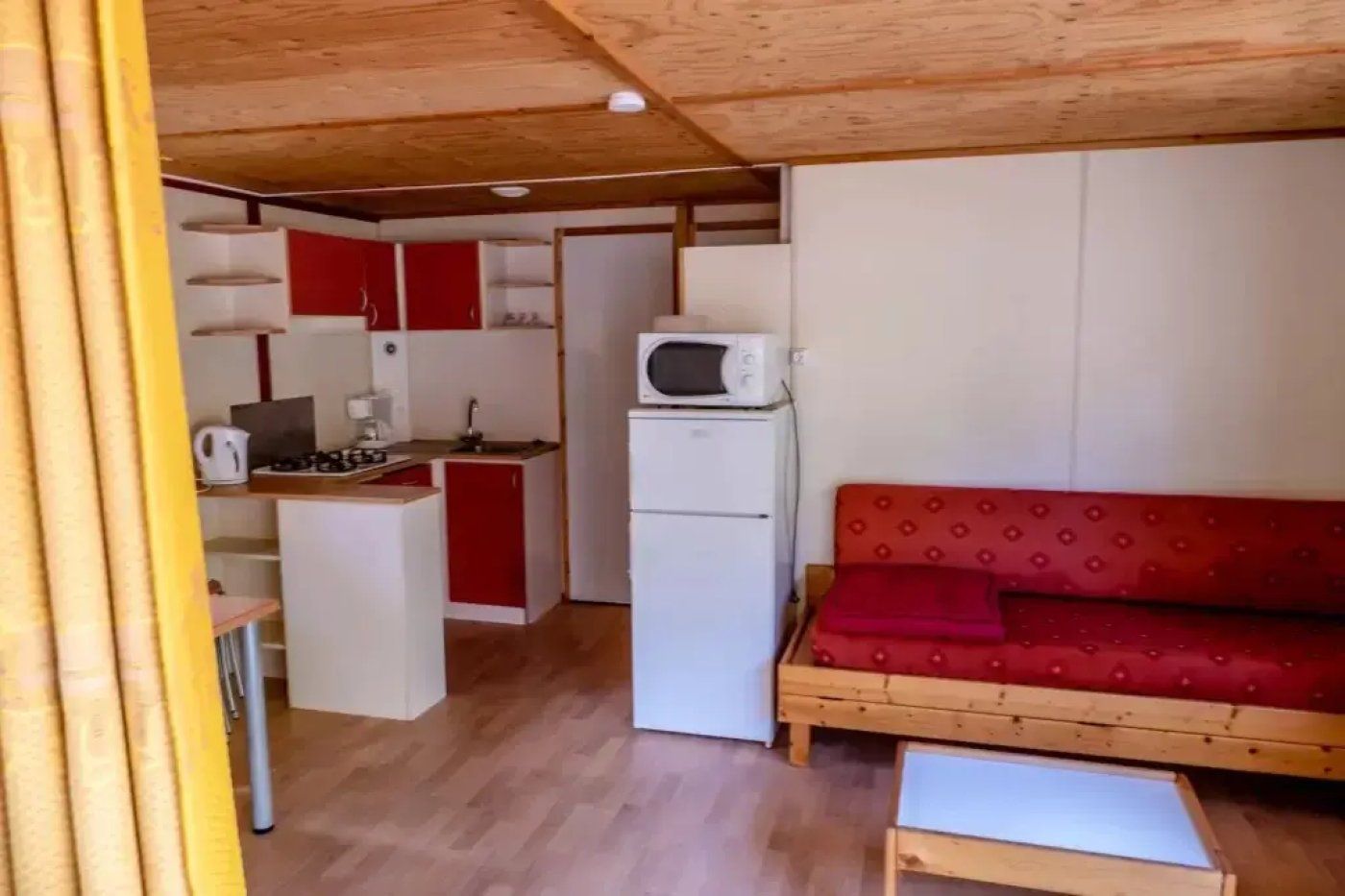 A compact living space with a kitchenette, a sofa, and a small table.
