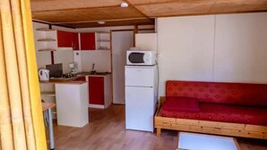 A compact living space with a kitchenette, a sofa, and a small table. - Chalet 2 étoiles - Piscine  - ccbgdfh (Porto-Vecchio)