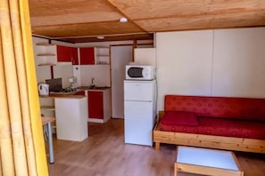 Un espacio habitable compacto con kitchenette, un sofá y una pequeña mesa.