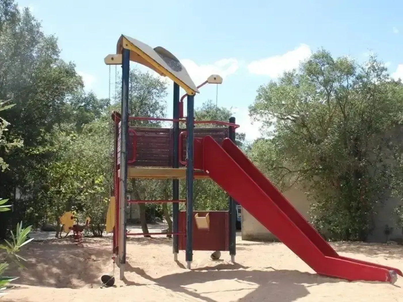 Un parque infantil con un tobogán rojo y una estructura para escalar.