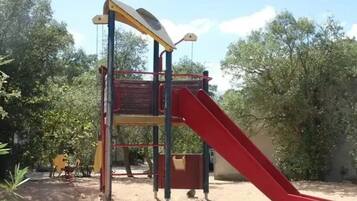 Un parque infantil con un tobogán rojo y una estructura para escalar.