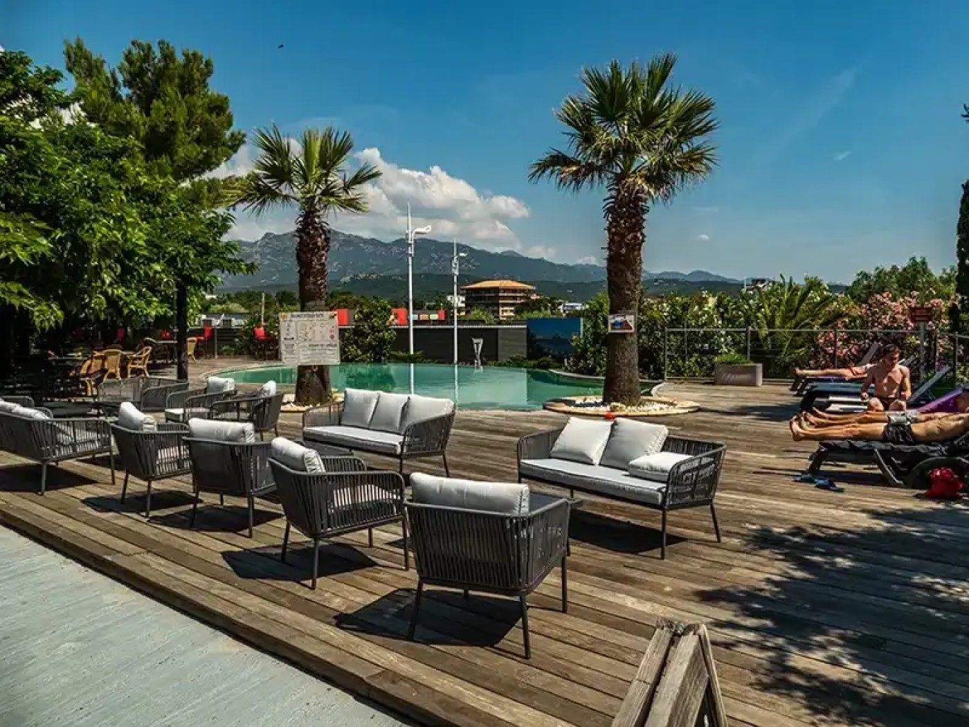 A poolside area with lounge chairs and a view of mountains.