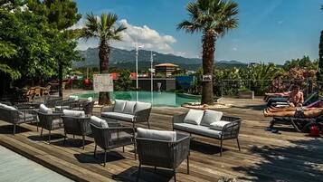 A poolside area with lounge chairs and a view of mountains.