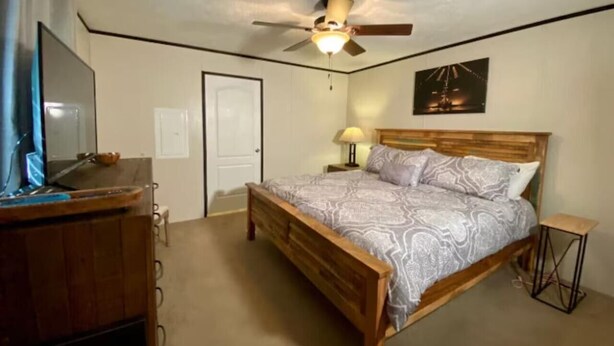A bedroom with a wooden bed, a ceiling fan, a desk, and a television. - Mountain Air #2438 (Pigeon Forge)