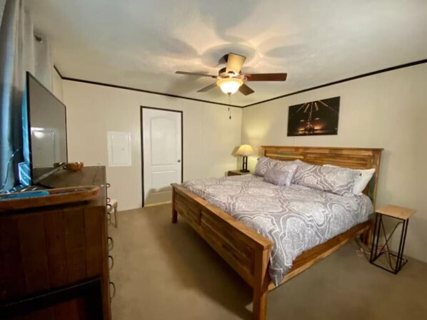 A bedroom with a wooden bed, a ceiling fan, a desk, and a television. - Mountain Air #2438 (Pigeon Forge)