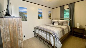 A bedroom with a metal bed frame, a bedside table, a lamp, and wall art. - Mountain Air #2438 (Pigeon Forge)