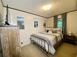A bedroom with a metal bed frame, a bedside table, a lamp, and wall art. - Mountain Air #2438 (Pigeon Forge)