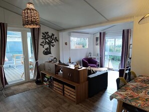 Ein modernes Wohnzimmer mit einem Holzschrank, einem violetten Sofa und einem Esstisch mit gemustertem Tischläufer.