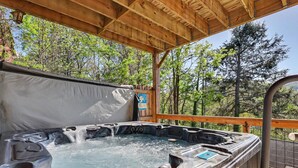 Ett bubbelbad under en träpergola med utsikt över träd.