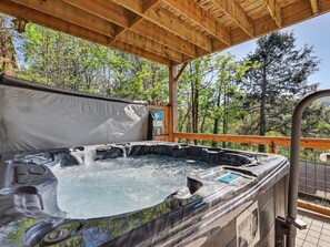Ein Whirlpool unter einer Holzpergola mit Blick auf Bäume.