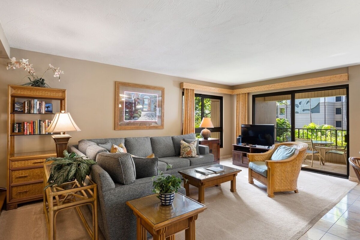 A living room with a sofa, coffee table, TV, and wicker furniture.