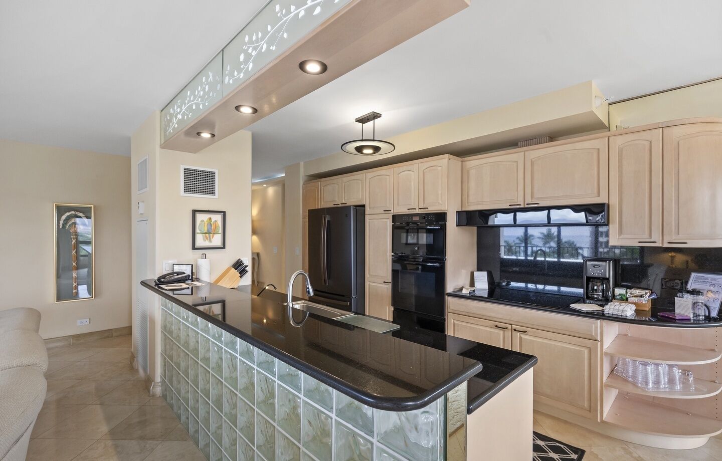 A modern kitchen with a central island, stainless steel appliances, and light wood cabinetry.