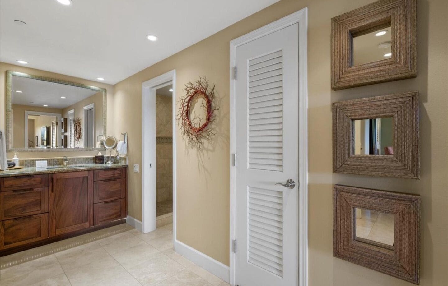 A bathroom with a vanity, mirror, and a door with louvered panels.