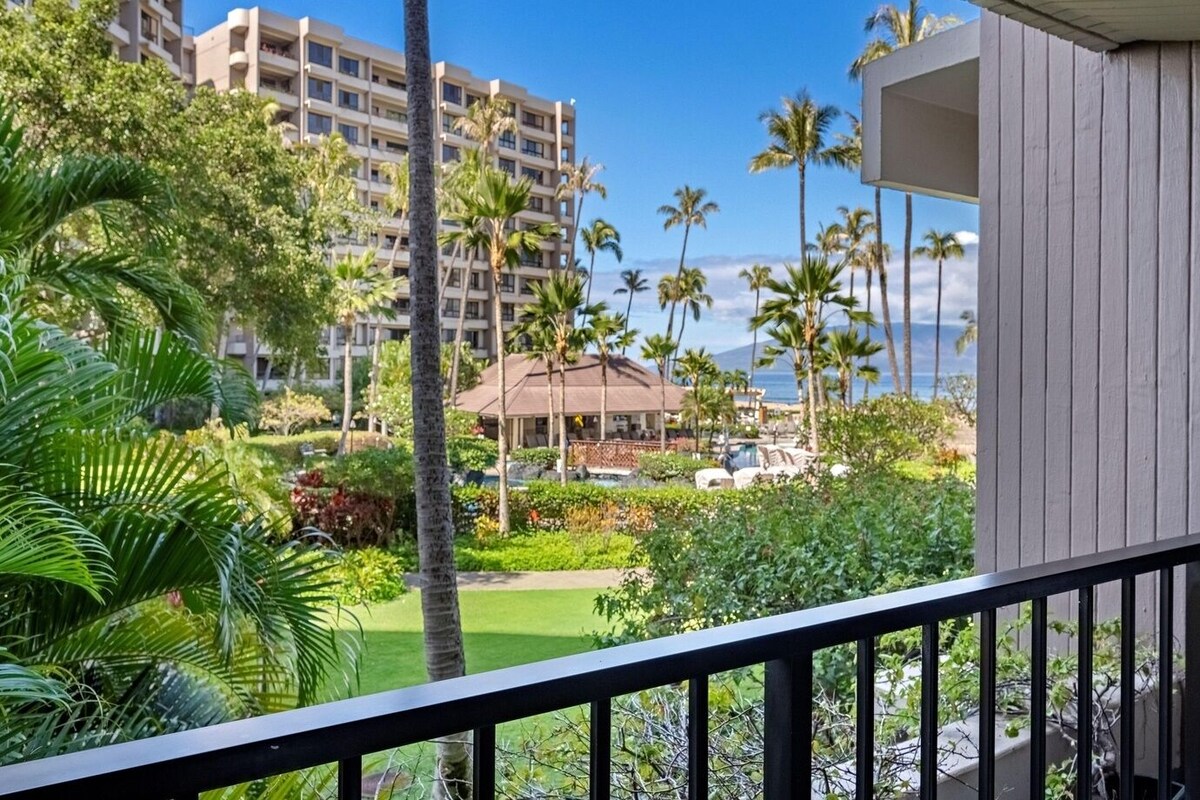 A hotel with a pool, palm trees, and a view of the ocean.