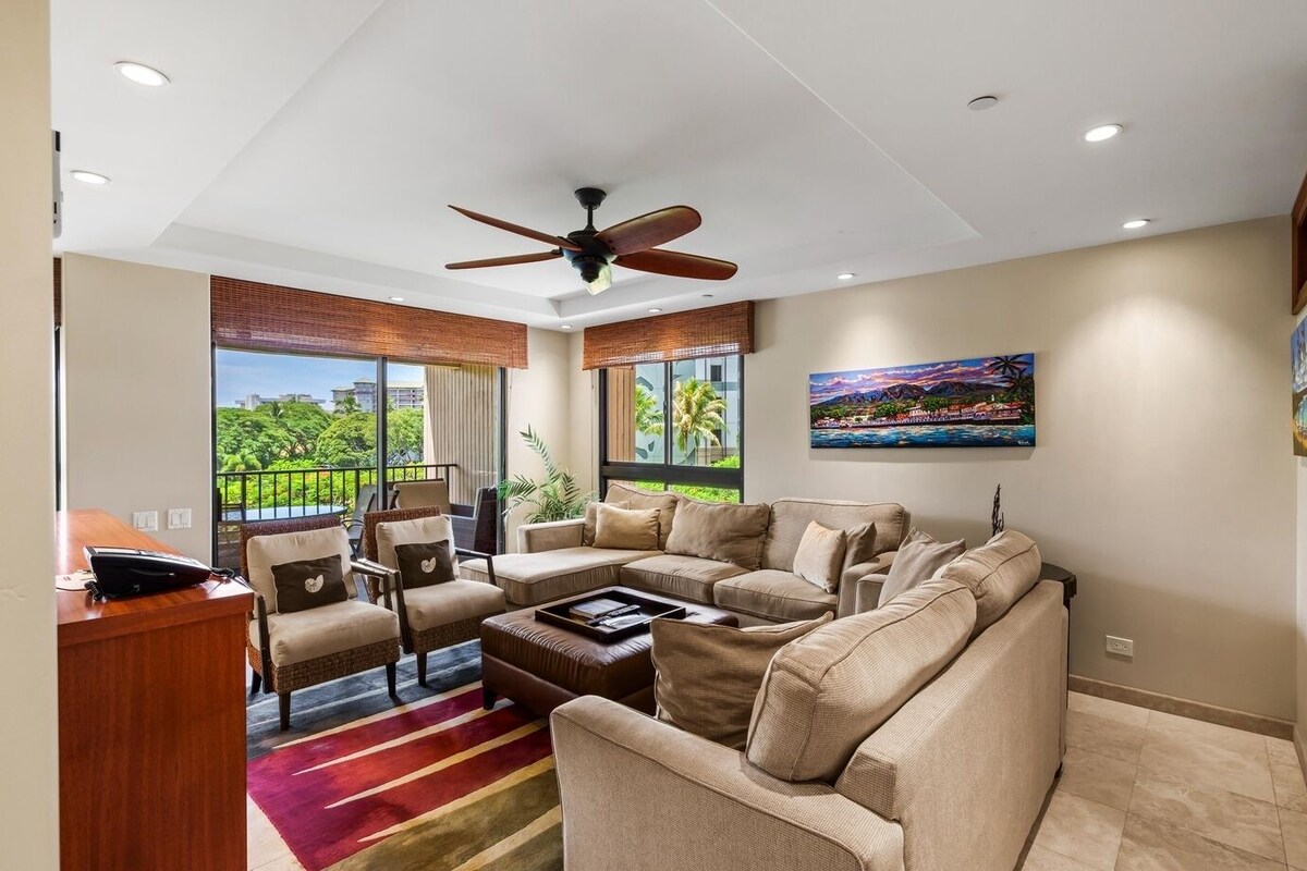 A modern living room with a sectional sofa, a desk, and a ceiling fan.