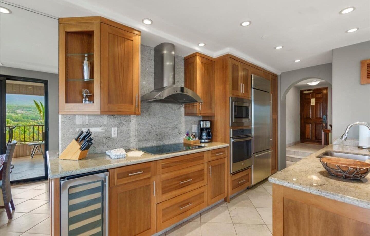 Una cocina moderna con gabinetes de madera, electrodomésticos de acero inoxidable y encimera de granito.