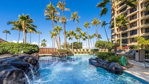 A swimming pool with water features, surrounded by palm trees and lounge chairs. - Kaanapali Alii-2 Bedroom Partial Ocean Views (Lahaina)