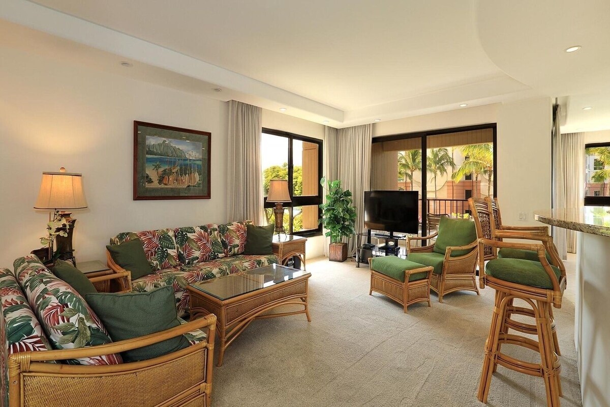 A living room with a sofa, chairs, a coffee table, a TV, and a painting on the wall.