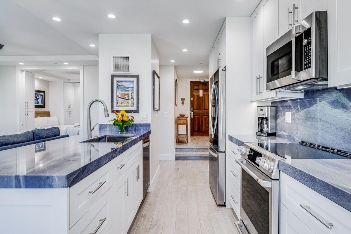 A modern kitchen with white cabinetry, a marble countertop, and stainless steel appliances.