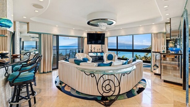 A luxurious living area with a curved seating arrangement, a dining area with a round table, and large windows offering ocean views. - Kaanapali Alii-2 Bedroom Ocean Front Views (Lahaina)