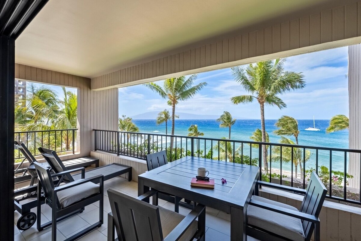 Ein Balkon mit Blick auf den Ozean, einem Tisch mit Stühlen und einer Couch.