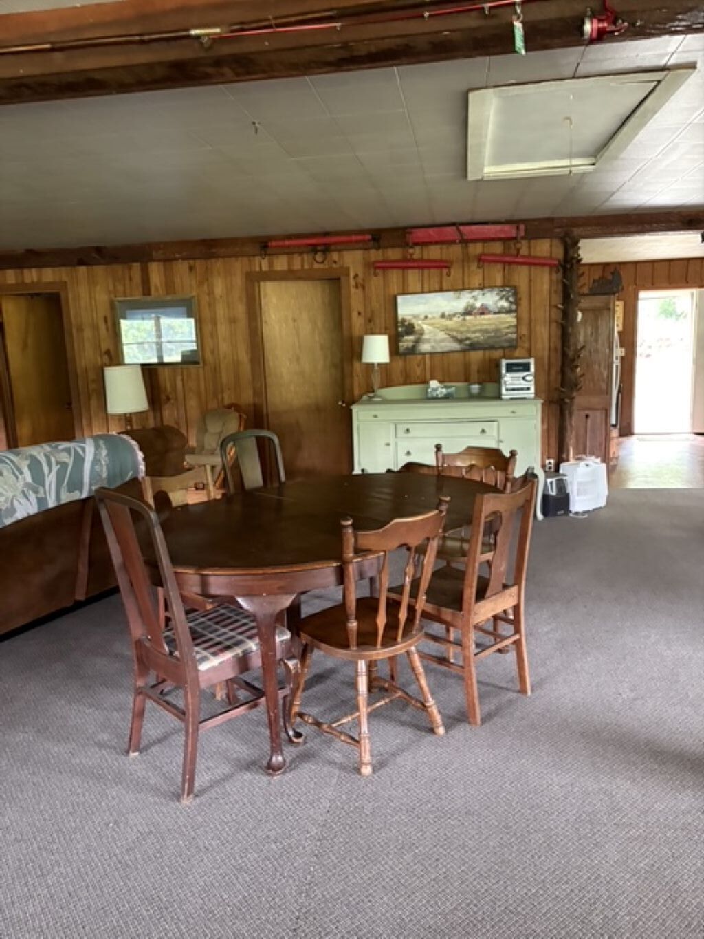 Une salle à manger en bois avec une table et des chaises, un canapé, une lampe et un tableau au mur.
