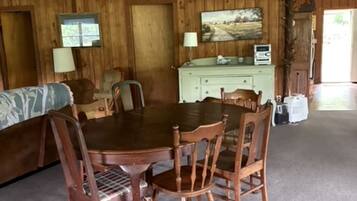 Une salle à manger en bois avec une table et des chaises, un canapé, une lampe et un tableau au mur.