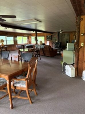A spacious room with a large wooden dining table, several chairs, a ceiling fan, and a television.