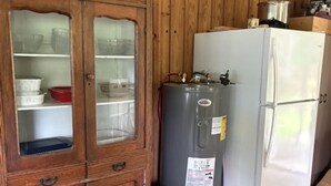 A kitchen with wooden paneling, a cabinet with glass doors, a gray water heater, a white refrigerator, and a wooden barrel. - Peaceful 2-bedroom cabin with AC in welcoming Villa Ridge (Villa Ridge)