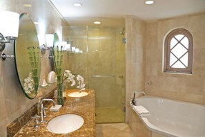 Ein Badezimmer mit einer großen Badewanne, zwei Waschbecken, einer Duschkabine aus Glas und einem großen Spiegel.