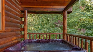 Eine Holzdiele mit Whirlpool auf einem Balkon mit Blick auf einen Wald.