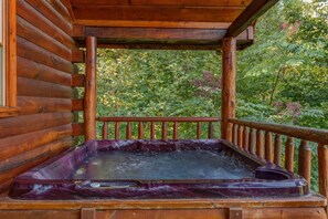 Eine Holzdiele mit Whirlpool auf einem Balkon mit Blick auf einen Wald.