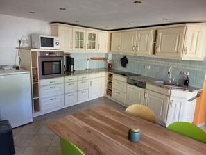 Une cuisine avec des meubles blancs, une table en bois et un four à micro-ondes.
