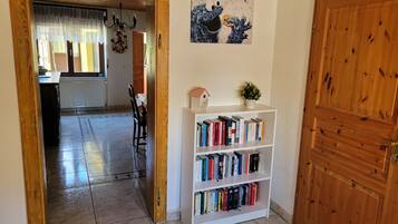 En hall med en trädörr, en bokhylla med böcker, en tavla och en matplats i bakgrunden.