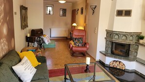 A living room with a sofa, a chair, a fireplace, and a radiator. - Cozy vacation apartment in the Hoher Fläming Nature Park with a spacious garden (Wiesenburg/Mark)