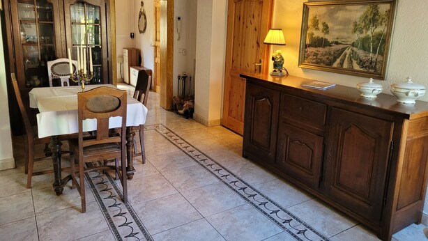 A dining area with a wooden table, chairs, a chandelier, a painting, and a cabinet. - Cozy vacation apartment in the Hoher Fläming Nature Park with a spacious garden (Wiesenburg/Mark)