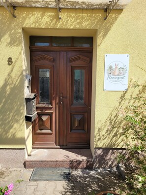 Une porte double en bois, avec une boîte aux lettres et une enseigne fixée au mur.