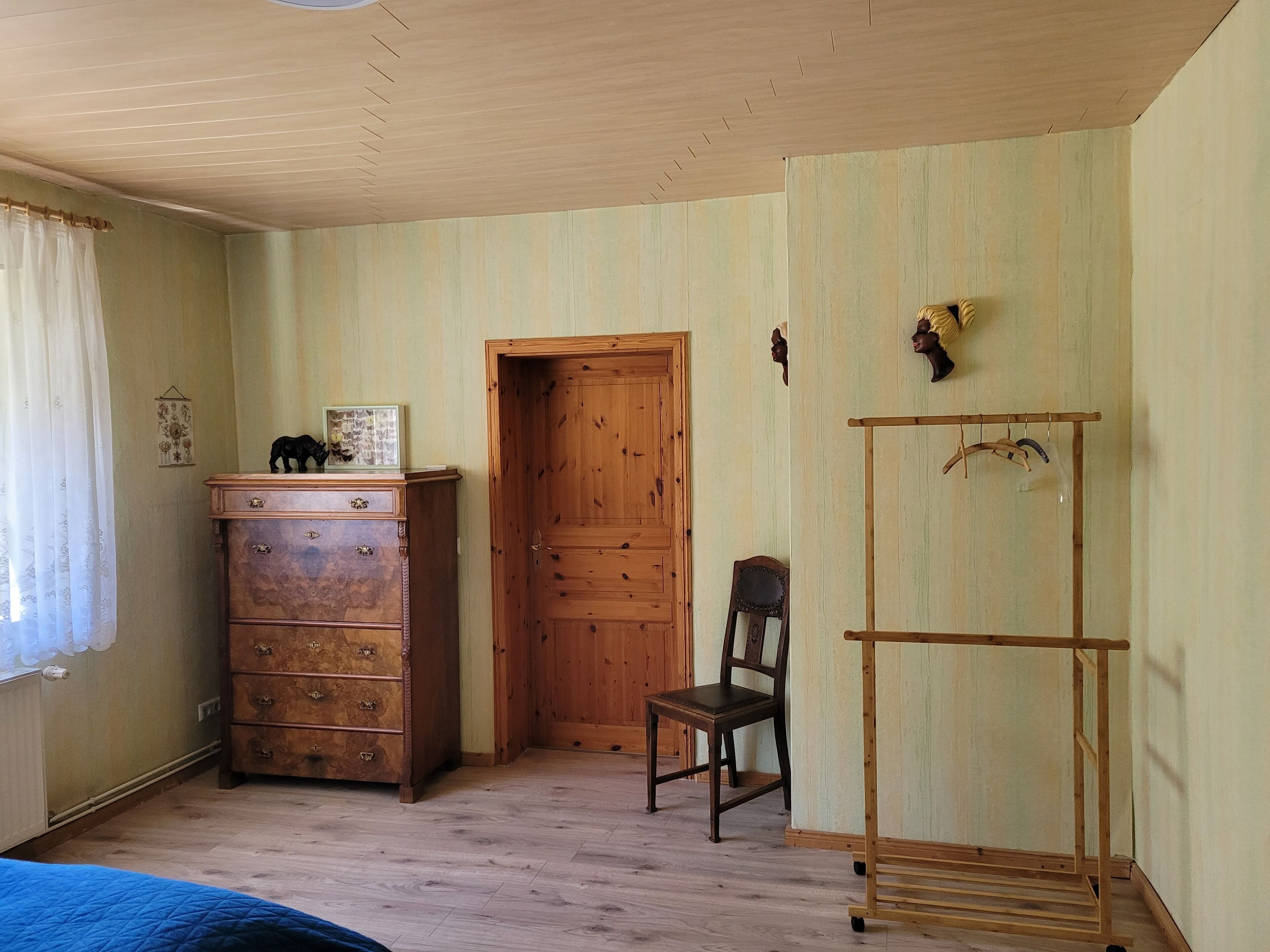 Una habitación con un aparador de madera, una silla, un armario de madera, una puerta y un ventilador de techo.