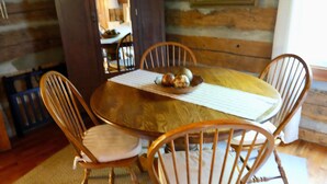 A wooden dining table with four chairs, a placemat, and a fruit bowl. - Granny's River Retreat #458 (Gatlinburg)