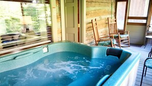 A hot tub with a wooden deck, a door, and two rocking chairs. - Granny's River Retreat #458 (Gatlinburg)