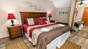 A bedroom with a wooden headboard, a red and white bedspread, two bedside lamps, a mirror, and a decorative wall sign. - Winter Haven #1903 (Gatlinburg)