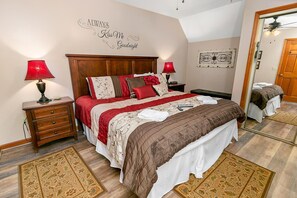 Ein Schlafzimmer mit h ölzernem Kopfteil, einer rot-weißen Bettdecke, zwei Nachttischlampen, einem Spiegel und einem dekorativen Wandschild.
