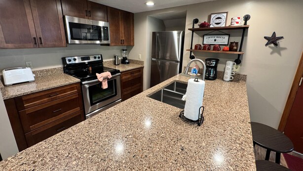 A modern kitchen with granite countertops, stainless steel appliances, and wooden cabinets. - Winter Haven #1903 (Gatlinburg)