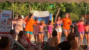 Un gruppo di persone riunito sotto una tenda, con una pubblicità di Kinder Ice Cream ben visibile.